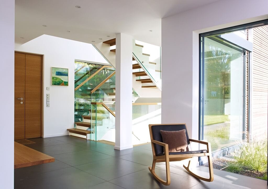 Eingangsbereich mit Innentreppe offen, minimalistisch mit mit viel Glas & Holz - Haus Design Ideen Inneneinrichtung Fertighaus Villa Crichton von Baufritz - HausbauDirekt.de