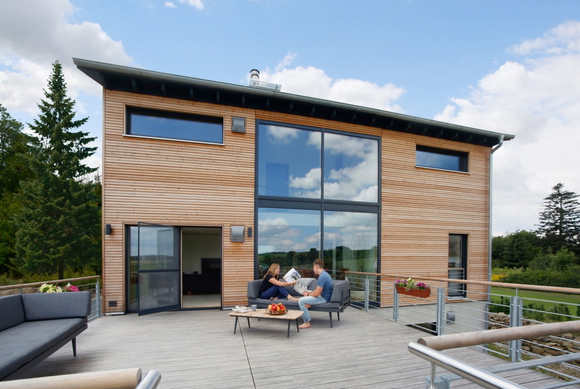 Modernes Holzhaus mit Galerie, Holz Fassade & großer Dachterrasse über Garage - Fertighaus bauen Ideen Baufritz Haus SCHELLENBERG - HausbauDirekt.de