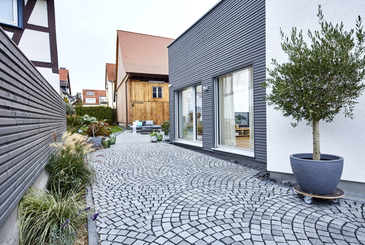 Moderner Erker Anbau mit Holz Fassade & Innenhof gepflastert - Fertighaus bauen Ideen ökologisches Baufritz Haus STADTHAUS EHRMANN - HausbauDirekt.de